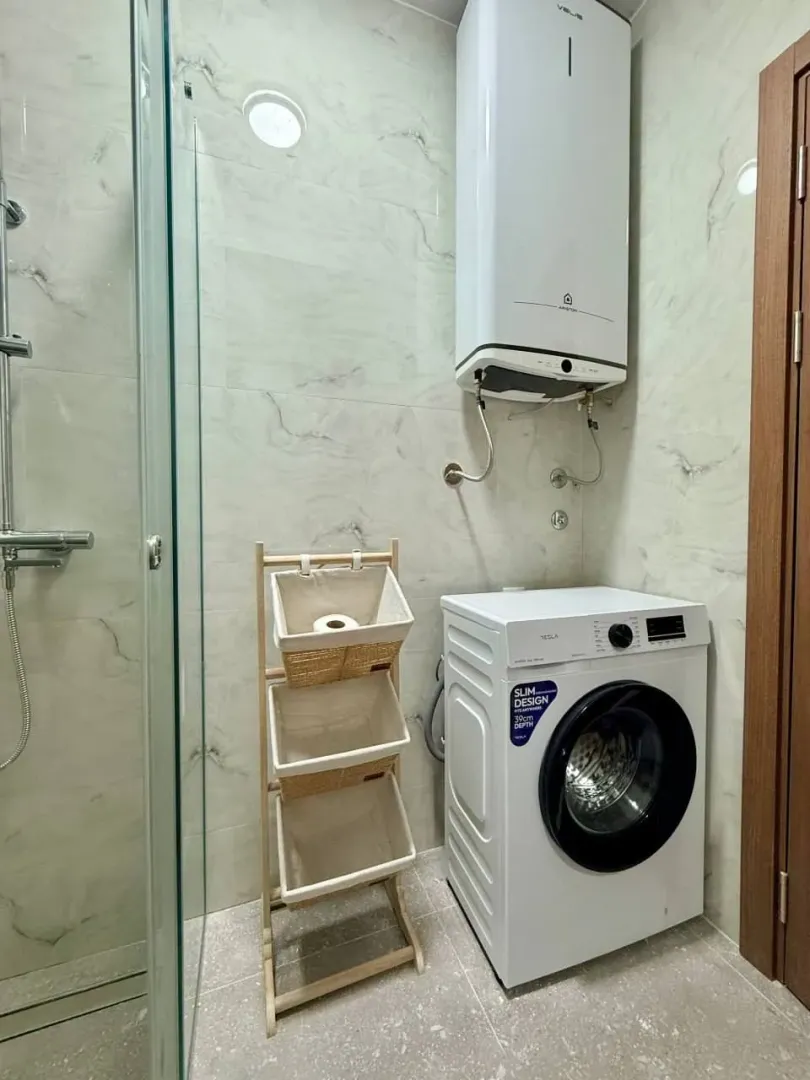 Bathroom with a shower cabin, water heater, and washing machine.
