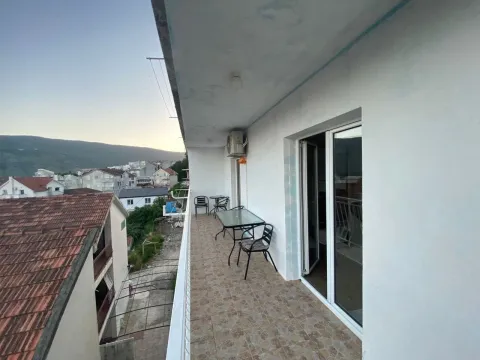 Dugačak natkriveni balkon sa stolom, stolicama i pogledom na naselje. - image 12