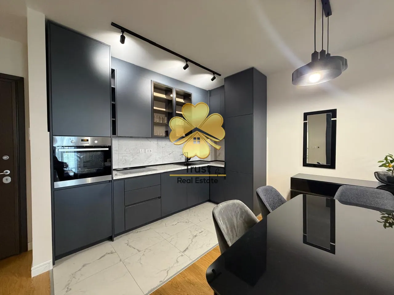 Modern kitchen with dark cabinetry and a dining table.