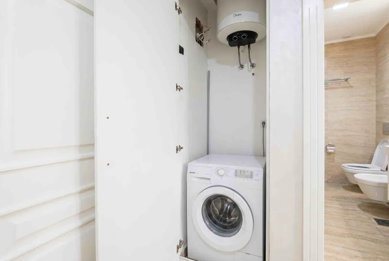 Bathroom with a washing machine and water heater in a niche.