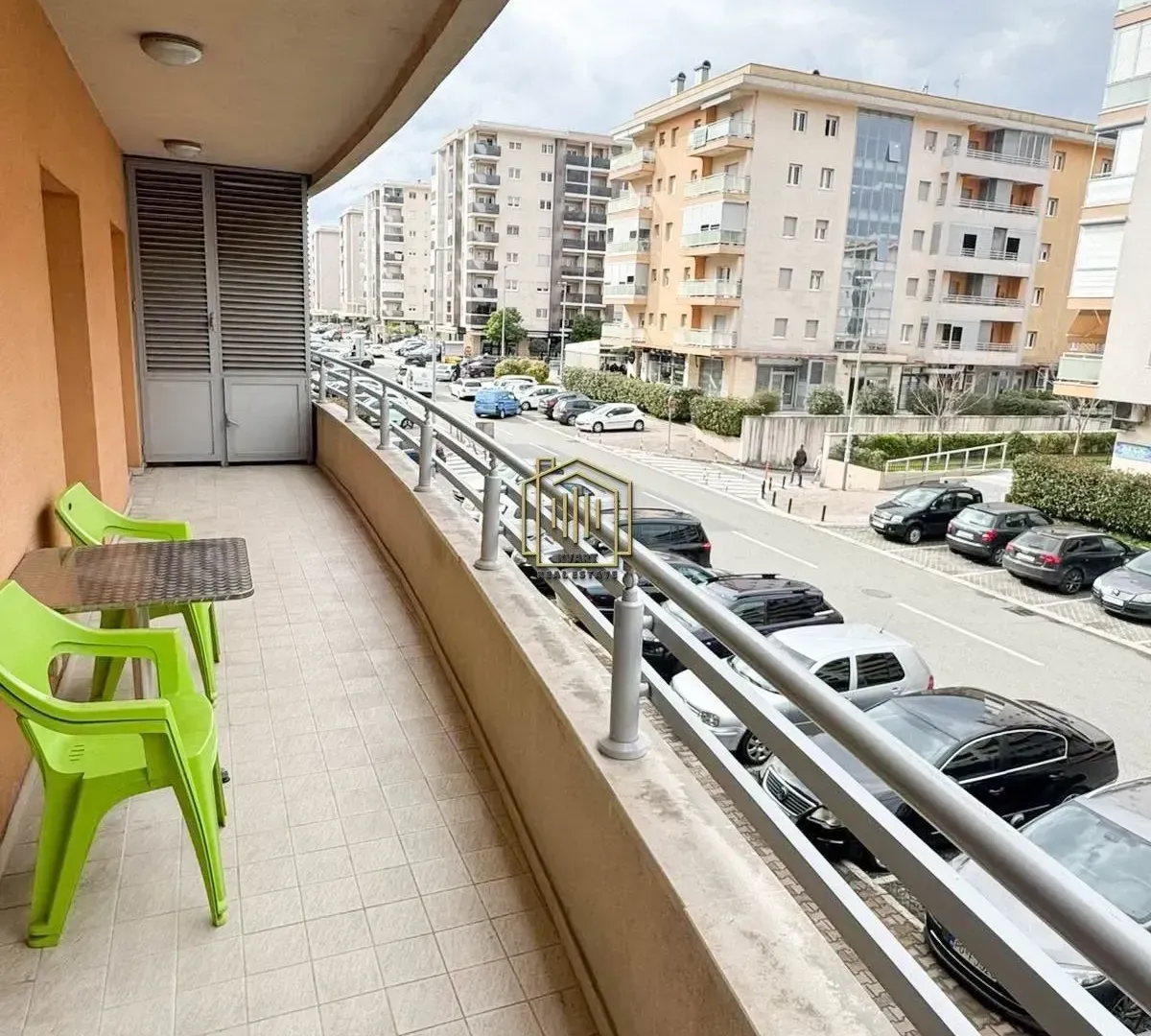Dugačak popločani balkon sa garniturom za sjedenje i pogledom na ulicu.