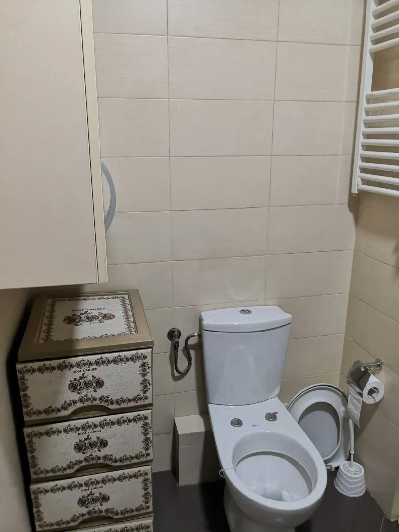 Jednostavno kupatilo sa toaletom i komodom za odlaganje.