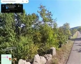 Pogled sa ulice na plac prekriven zelenilom.