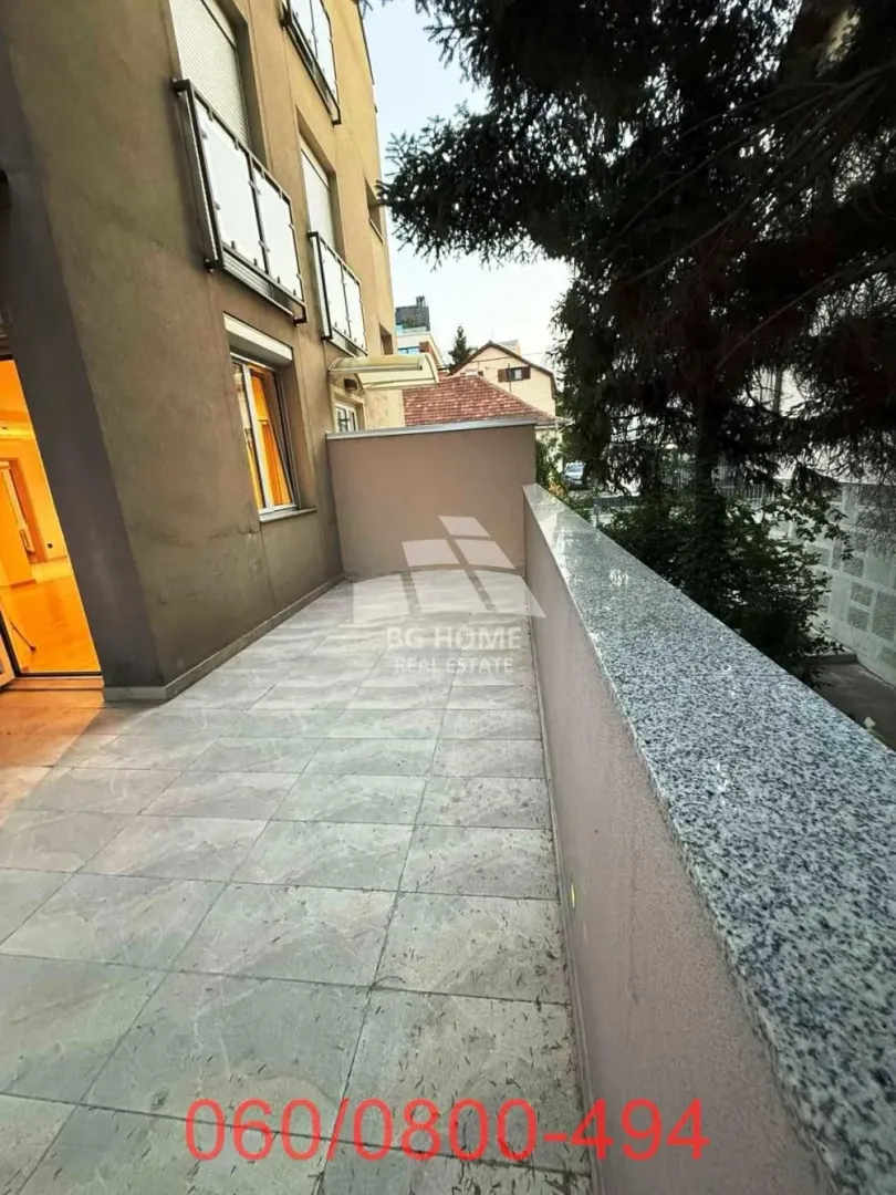 Prostrana popločana terasa sa ogradom i pogledom na okolinu.