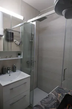 Bright bathroom featuring a glass shower cabin and a sink vanity. - image 7