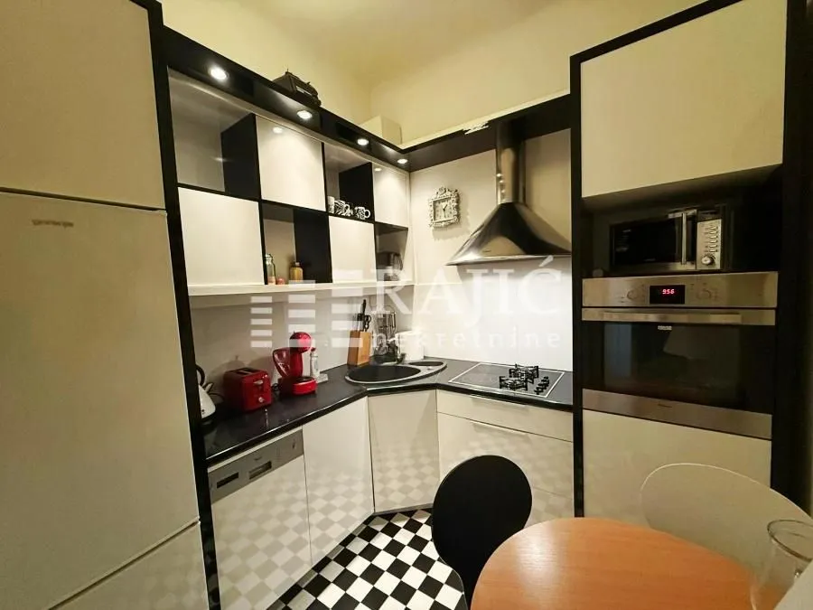 Modern kitchen with white and black elements and built-in appliances.