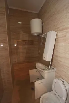Kupatilo sa keramičkim pločicama toplih tonova, lavaboom i bojlerom. - image 20