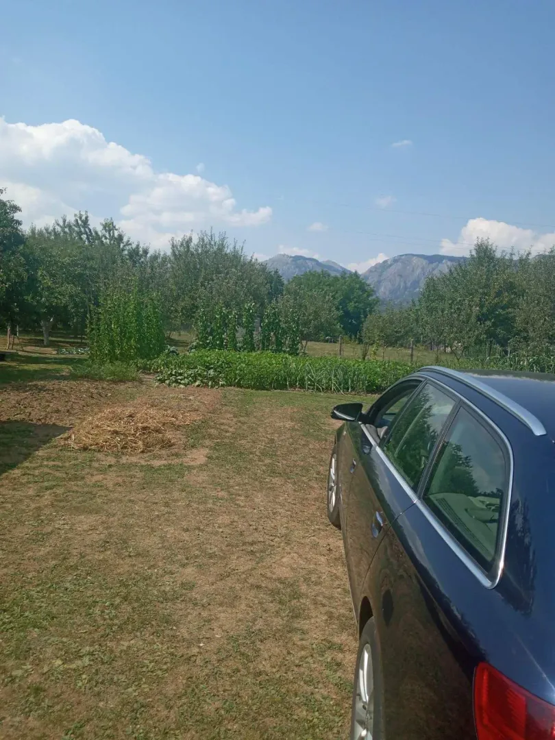 Prostrano dvorište sa zelenilom i pogledom na planine u daljini.