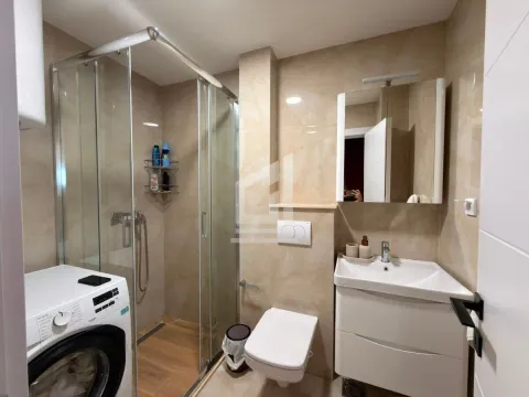 Modern bathroom with a walk-in shower, washbasin, and washing machine. - image 12