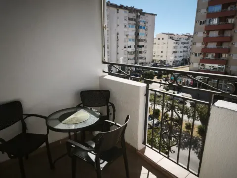 Manji namješteni balkon sa stočićem i stolicama i pogledom na grad. - image 11