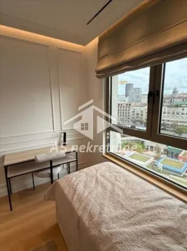 Smaller bedroom with a bed, desk, and a large window with a city view. - image 13