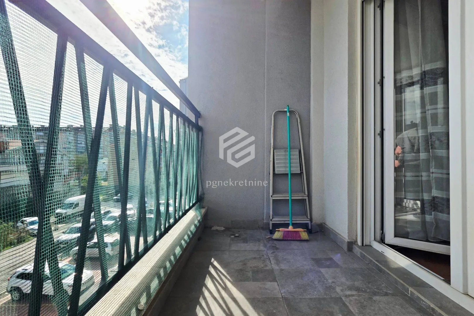 Small balcony with metal railing and street view.