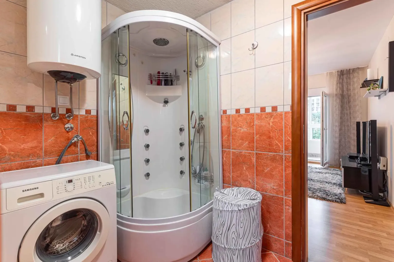 Bathroom with a shower cabin, water heater, and washing machine.
