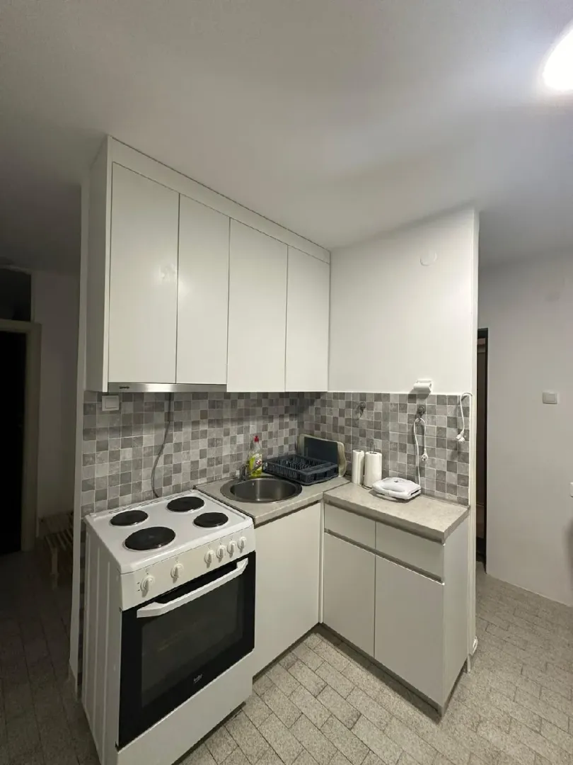 Smaller white kitchen with a stove and sink.