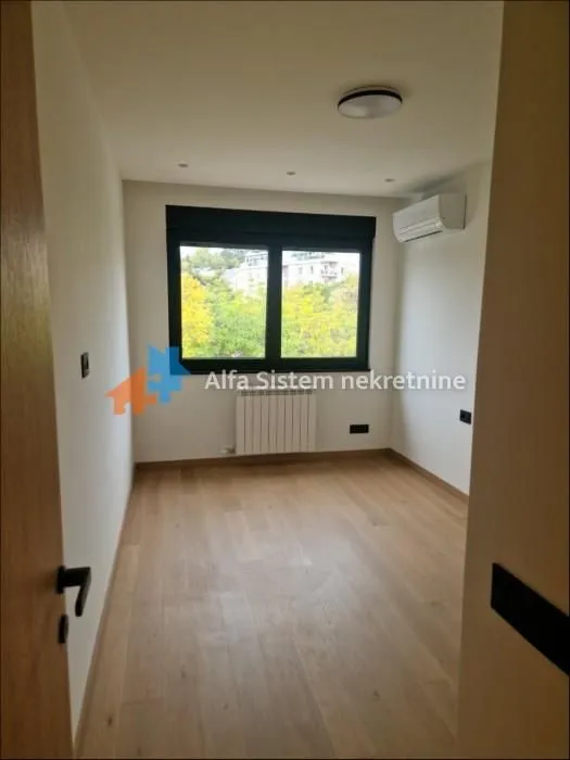 Empty room with hardwood floors, a window, and an air conditioning unit.