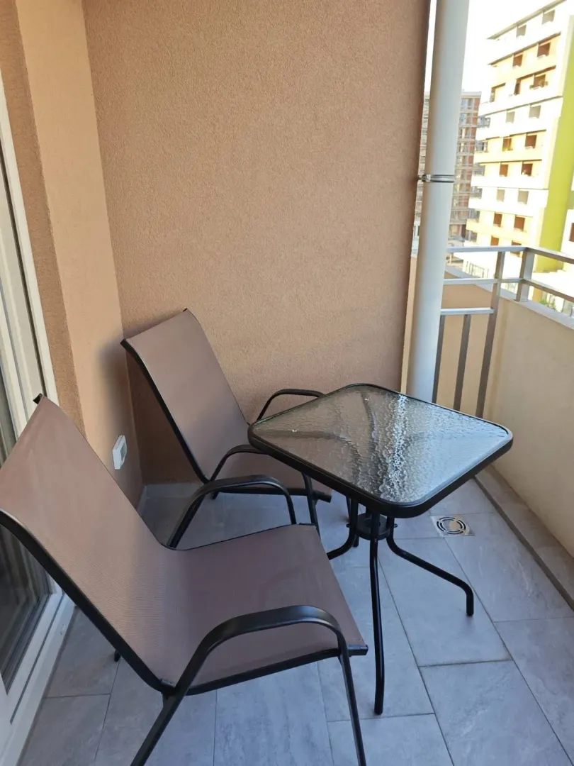Balkon sa dvije stolice i malim staklenim stolom.
