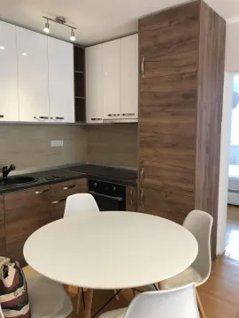 Modern kitchen with white and wooden cabinets and a dining table. - image 3