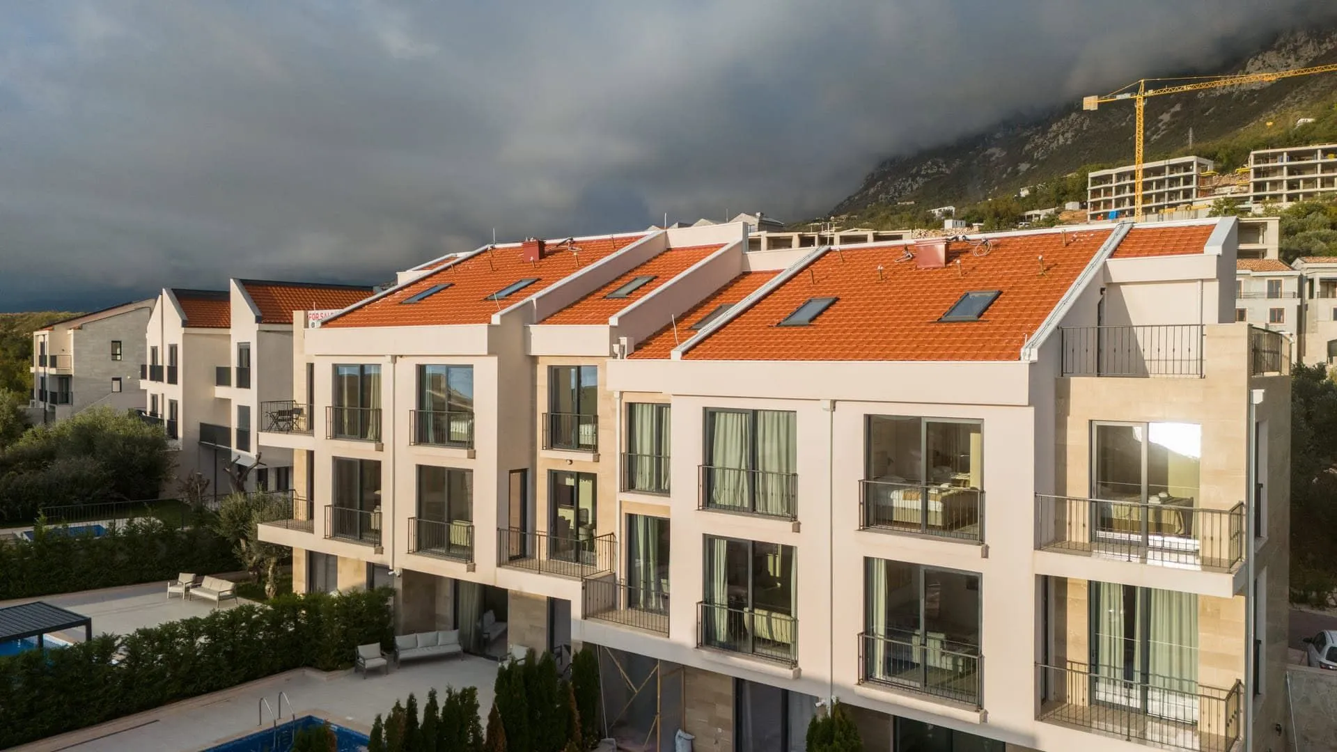Aerial view of the exterior of a modern residential building with balconies and a swimming pool.