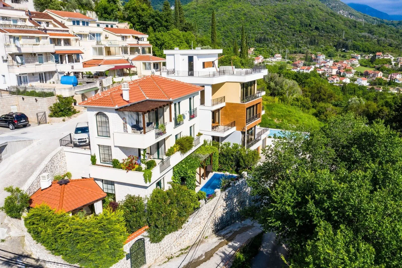 Pogled iz vazduha na kuću sa bazenom okruženu zelenilom.