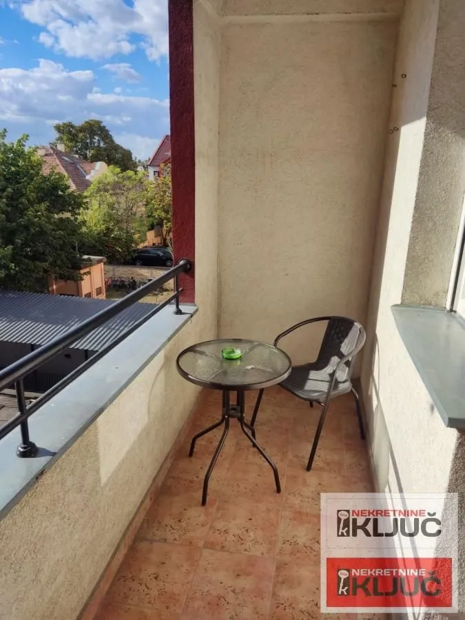 Manji namešteni balkon sa stolom i stolicom i pogledom na okolinu.