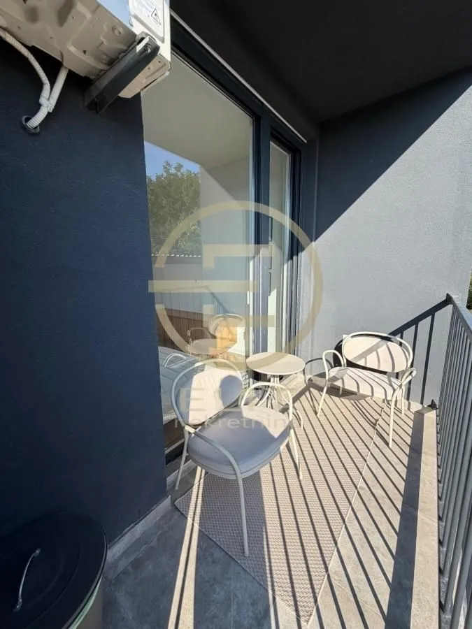 Namešten balkon sa garniturom za sedenje i staklenom balkonskom ogradom.