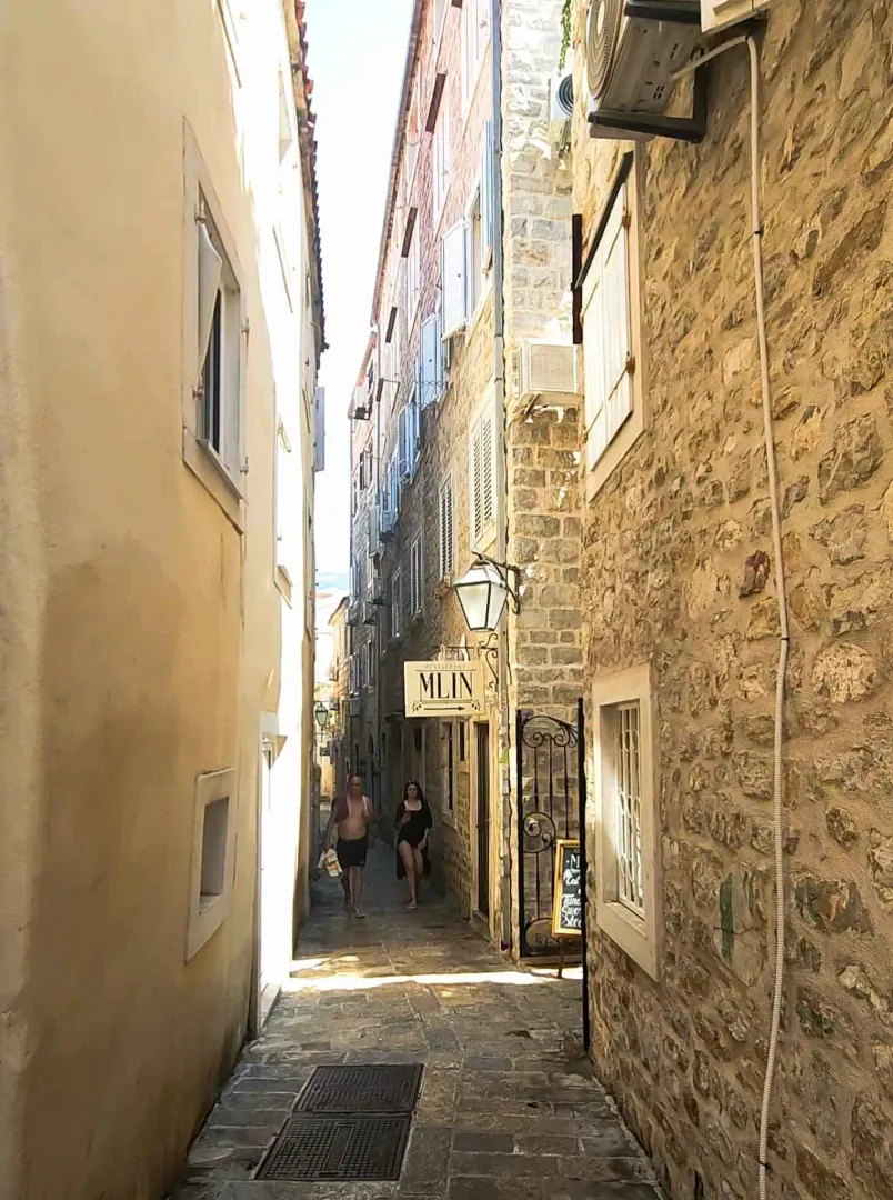 Narrow street with old stone buildings in a Mediterranean style.