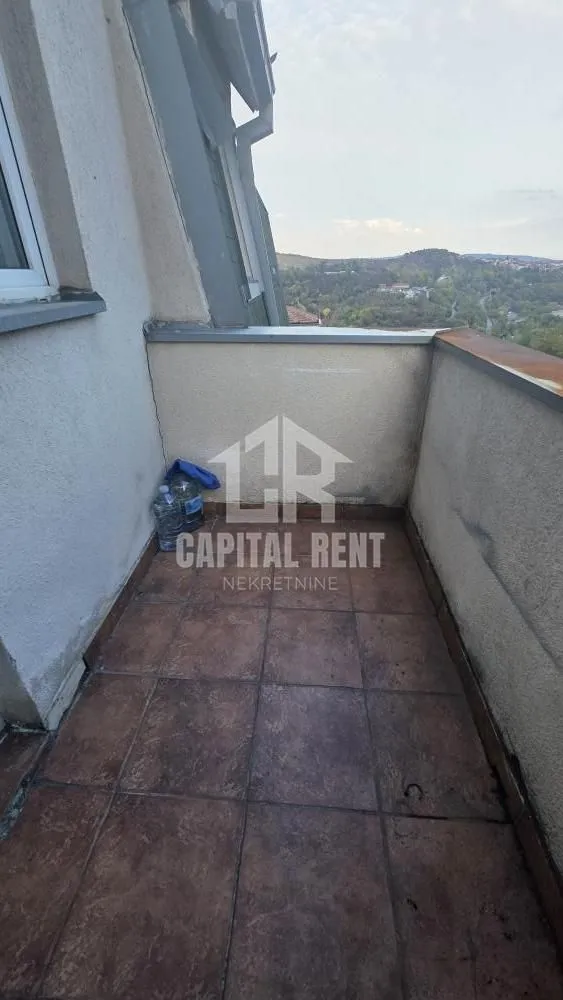 Manji popločani balkon sa pogledom na okolno zelenilo i brda.