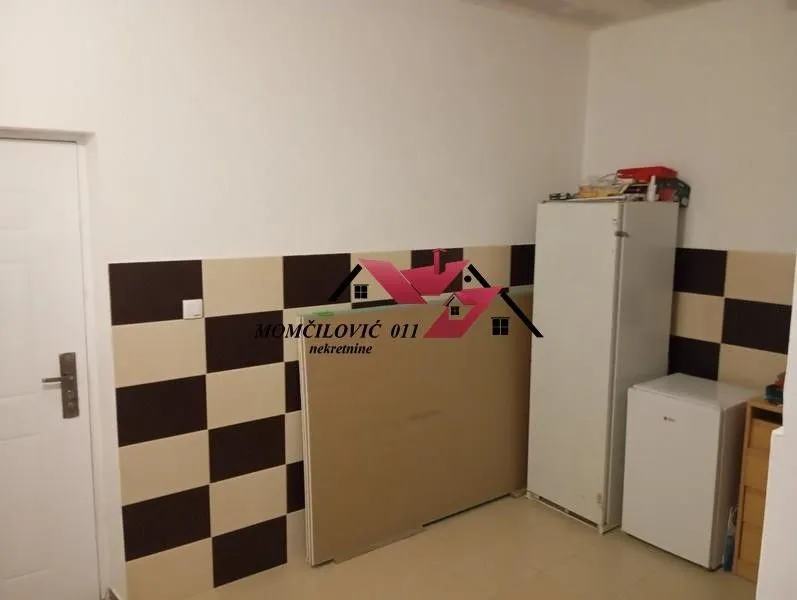 Small kitchen with checkered tiles and a refrigerator.