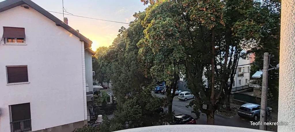 View from the terrace towards the neighbouring building and green trees.