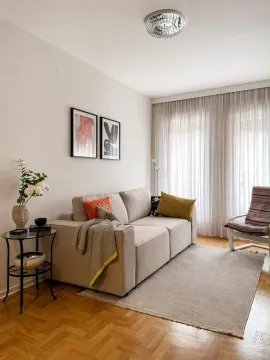 Living room with a sofa, rug, and large windows with curtains. - image 2