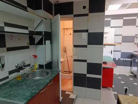 Kitchen with a sink, black and white patterned tiles, and a door leading to another room. - image 9