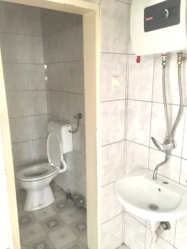 View of the bathroom with a washbasin, water heater, and a toilet in the separate area. - image 13
