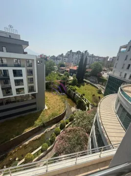 Pogled sa terase na okolne zgrade i zelenu površinu sa potokom. - image 10