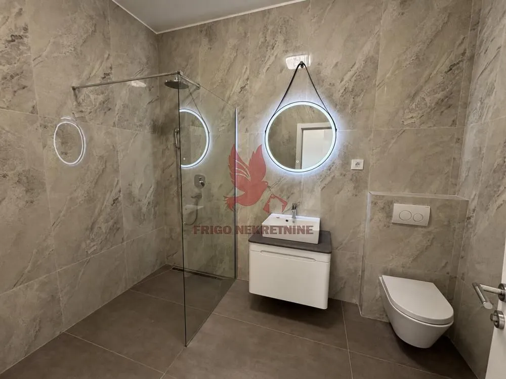 Moderno kupatilo sa tuš kabinom, umivaonikom i ugradnom wc šoljom.
