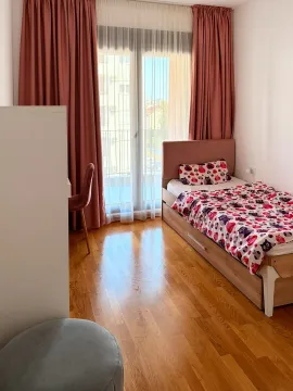 Manja spavaća soba sa krevetom, radnim stolom i prozorom sa roze zavjesama. - image 6