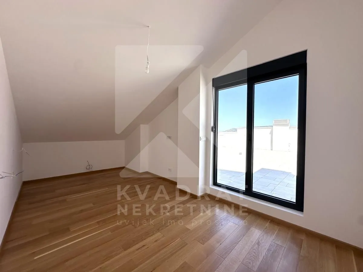Empty attic room with parquet flooring and access to the terrace.