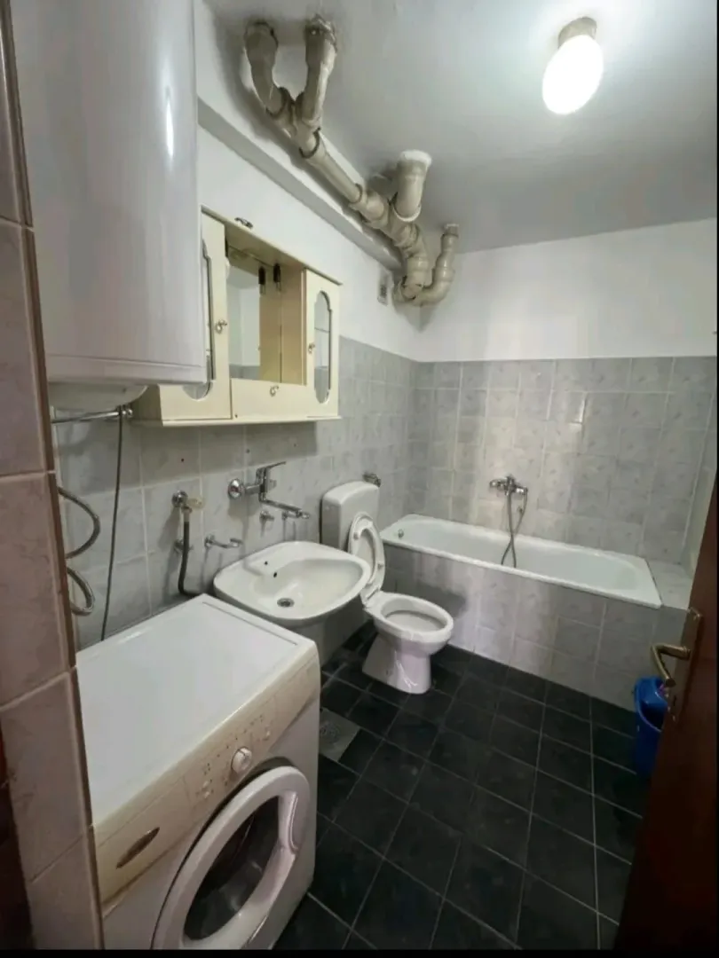 Smaller equipped bathroom with a bathtub, sink, and washing machine.