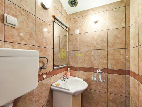 Small bathroom tiled in brown ceramic tiles with a washbasin and a mirror. - image 19