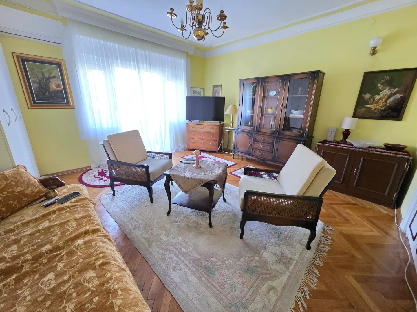 Furnished living room with seating set and wooden display cabinets.