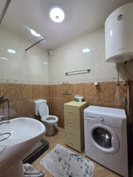 Bathroom equipped with a sink, toilet, shower cabin, and washing machine. - image 7