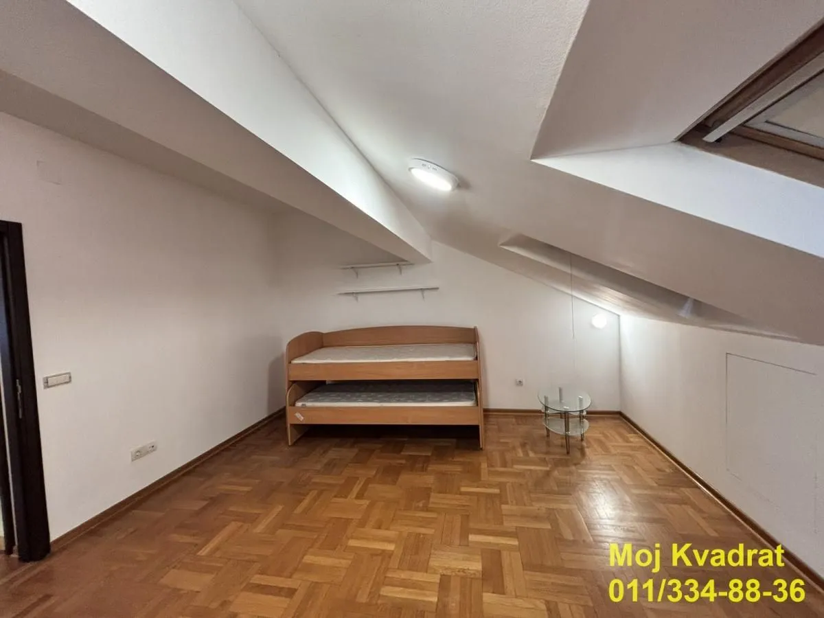 Potkrovlje sa drvenim krevetom i parketom na podu.