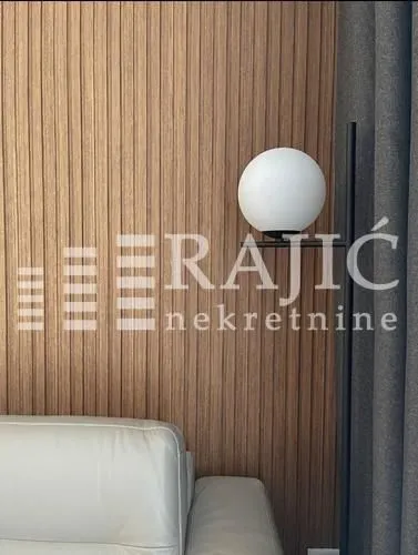 Interior detail of a living room with a wooden wall panel and a modern floor lamp.