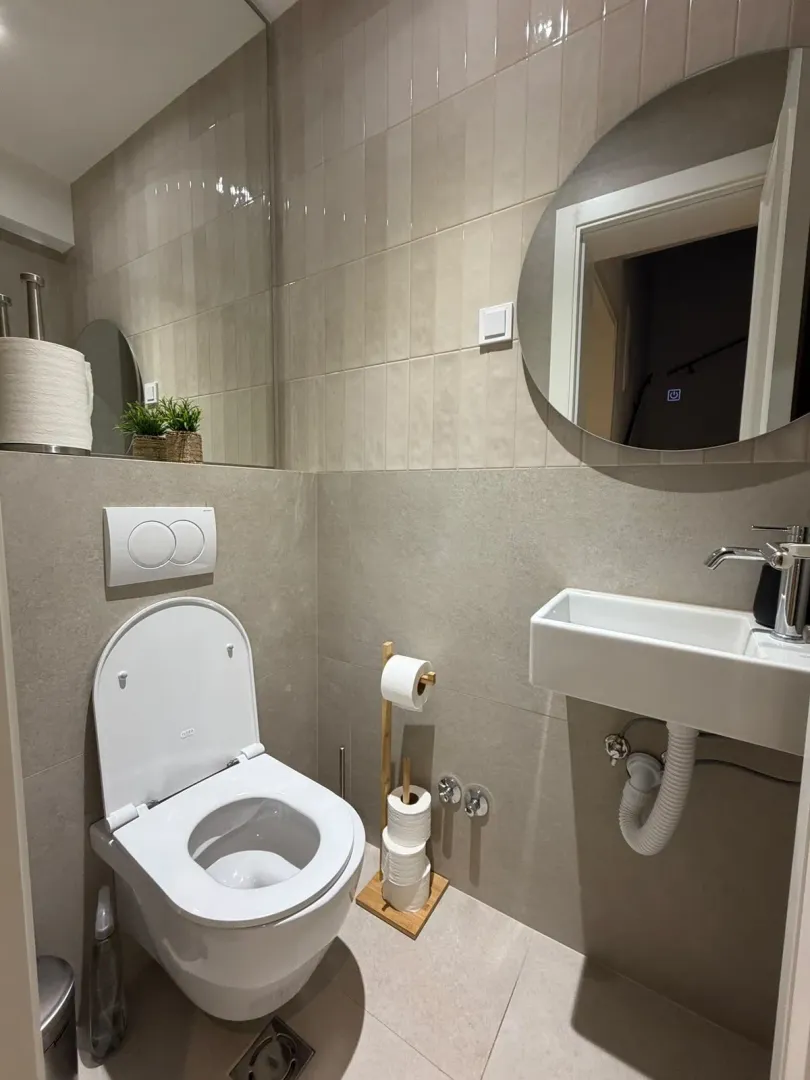 Moderne opremljeno kupatilo sa WC šoljom, umivaonikom i ogledalom.