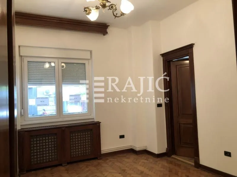 Empty room with parquet flooring, wooden trim, and a door.