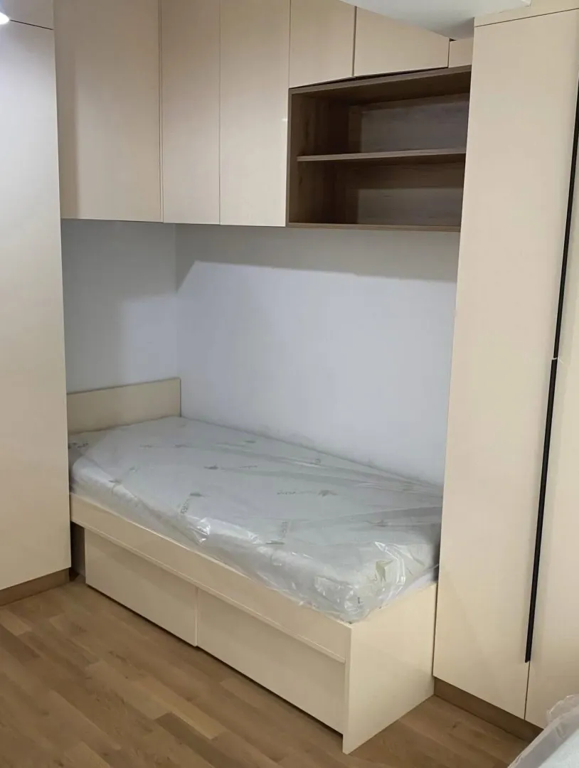 Manja spavaća soba sa ugrađenim krevetom i ormarima.