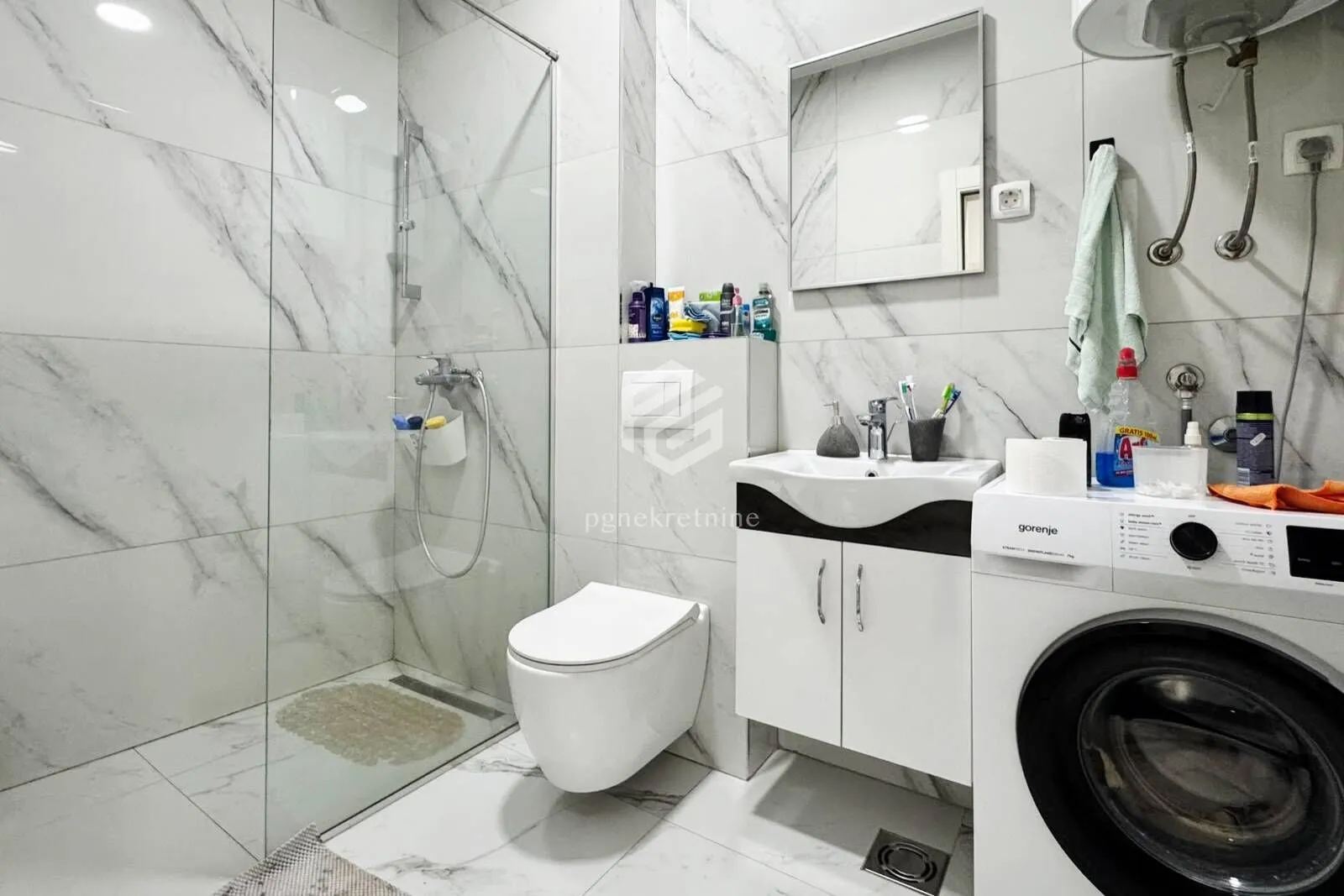 Modern bathroom equipped with a walk-in shower, washbasin, and washing machine.
