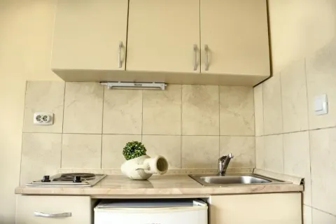 Small kitchen with a sink, built-in cooktop, and upper cabinets. - image 3