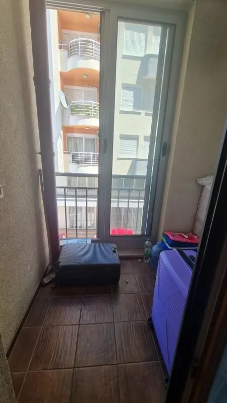 Manji popločani balkon sa koferima i pogledom na susjednu zgradu.
