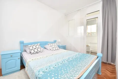 Spavaća soba sa plavim krevetom i noćnim stočićima i izlazom na terasu. - image 6