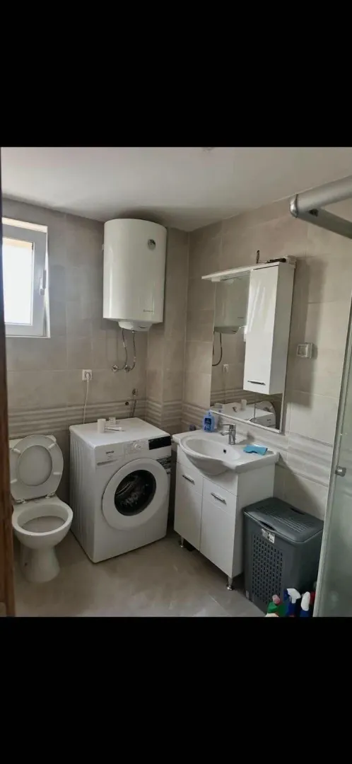 Compactly equipped bathroom with a washbasin, washing machine, and toilet.